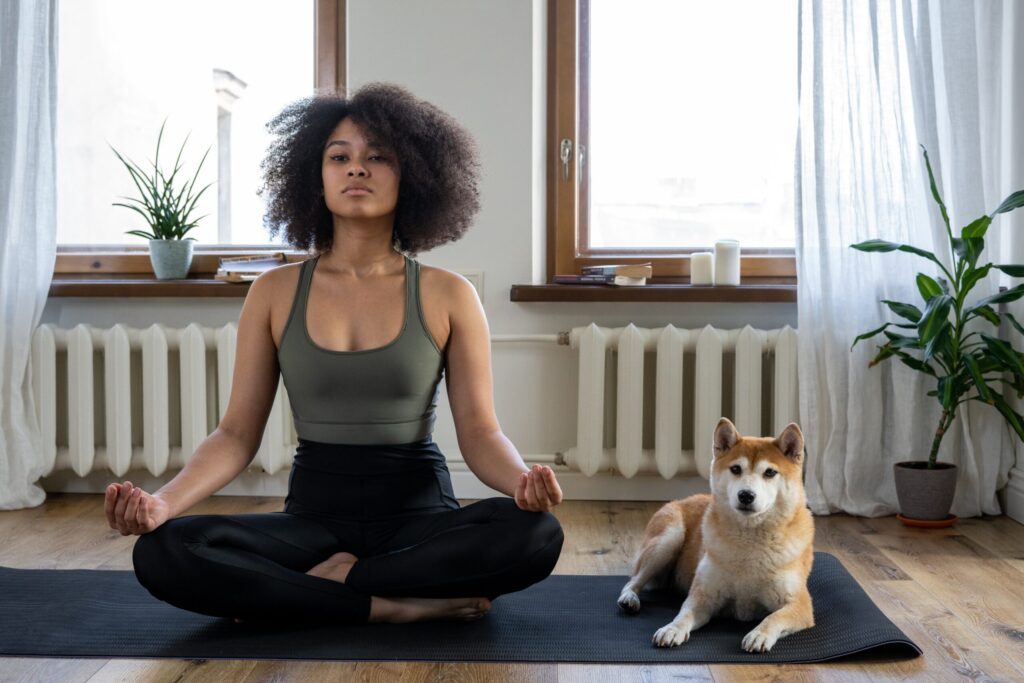 A Girl Doing Yoga with a dog sitting beside featured image for article on the 12 Benefits of Yoga to Boost Energy Levels and Mental Well-being on healthy and better living