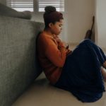 a black girl sitting on floor with hands on chest featured image in article chest pain from anxiety published on healthy n better living
