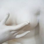 A hand pointing at breast - featured image on article on Breast Reduction Scars published on healthy n better living